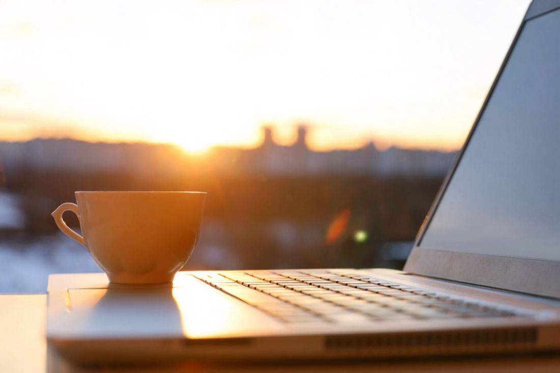 a coffee cup sitting on a laptop during flexible work hours