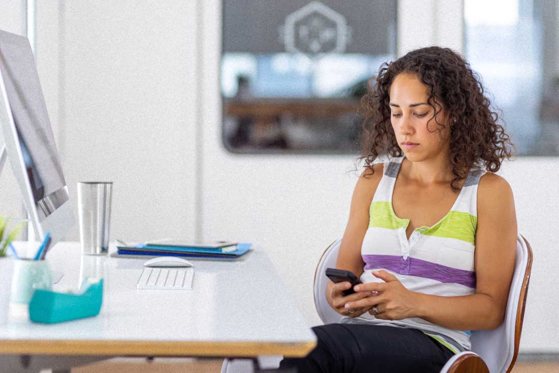 An employee of a disengaged workforce on her personal phone at work.