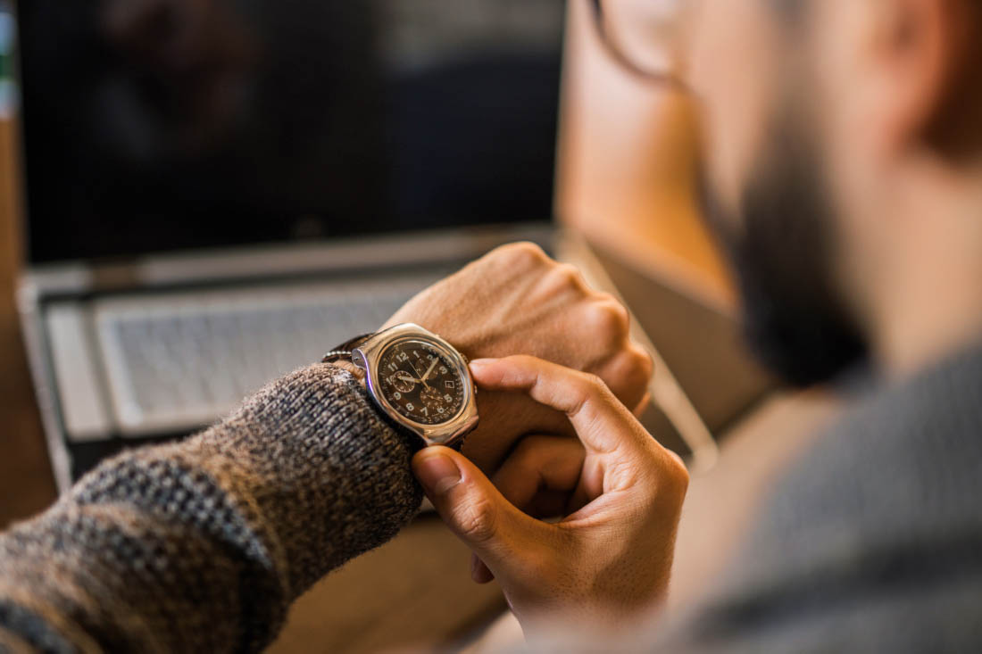 An employee checking his watch because time management is important in the workplace.